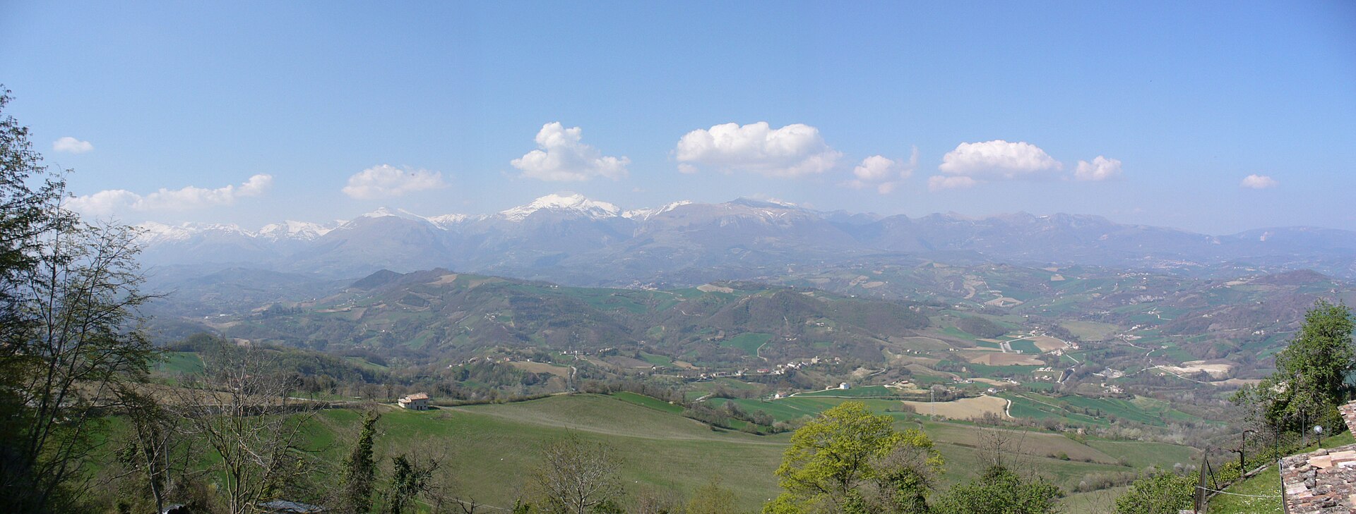 Le cime innevate dei Monti Sibillini oltre le colline verdi in primavera